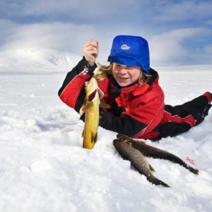 Fornøyd ung isfisker som løfter tredje ørret opp av hullet