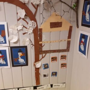 Kunst på veggen i barnehagen. Fuglebrett og tre laget i papir som henger inne på veggen til pynt.